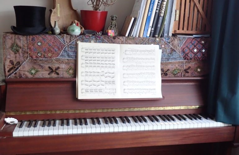 A piano with a music book and other objects on top