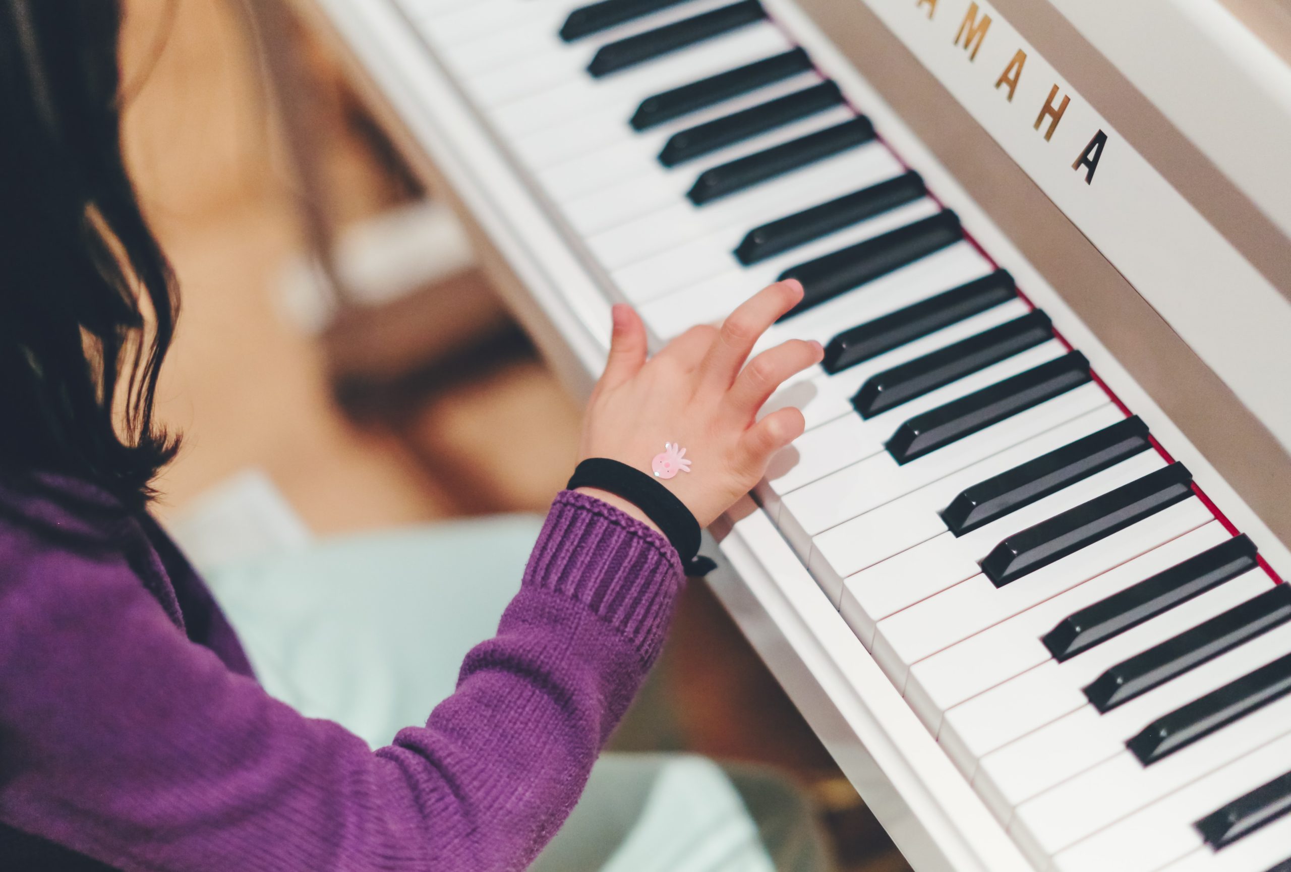 Close up on hand of child playing white piano
